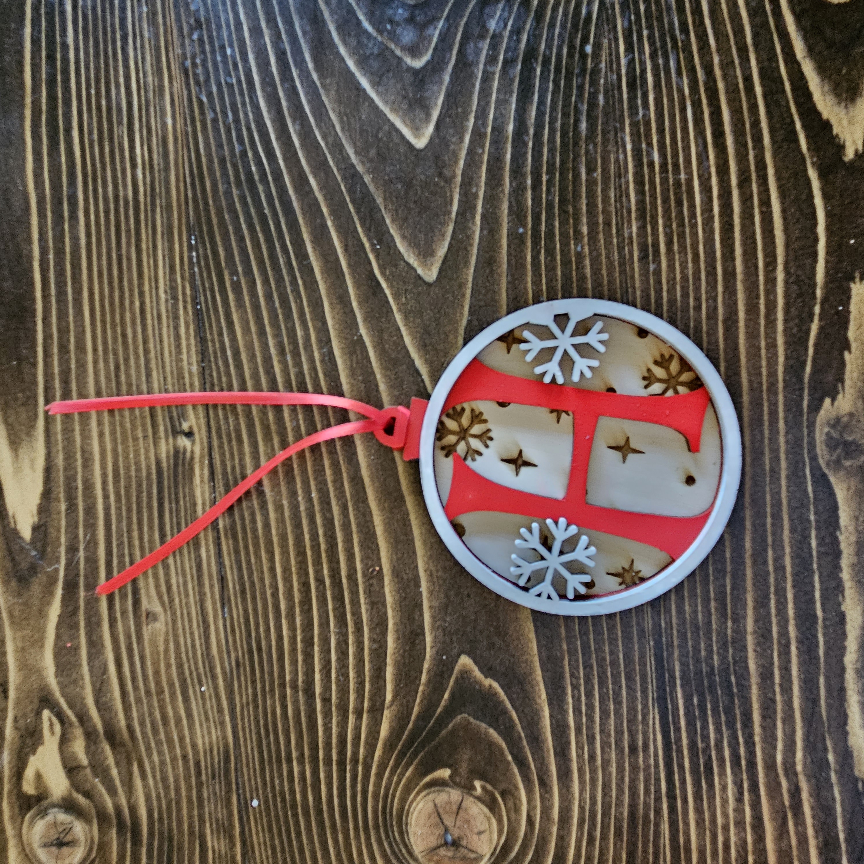 A snowflake-shaped ornament engraved with a monogram