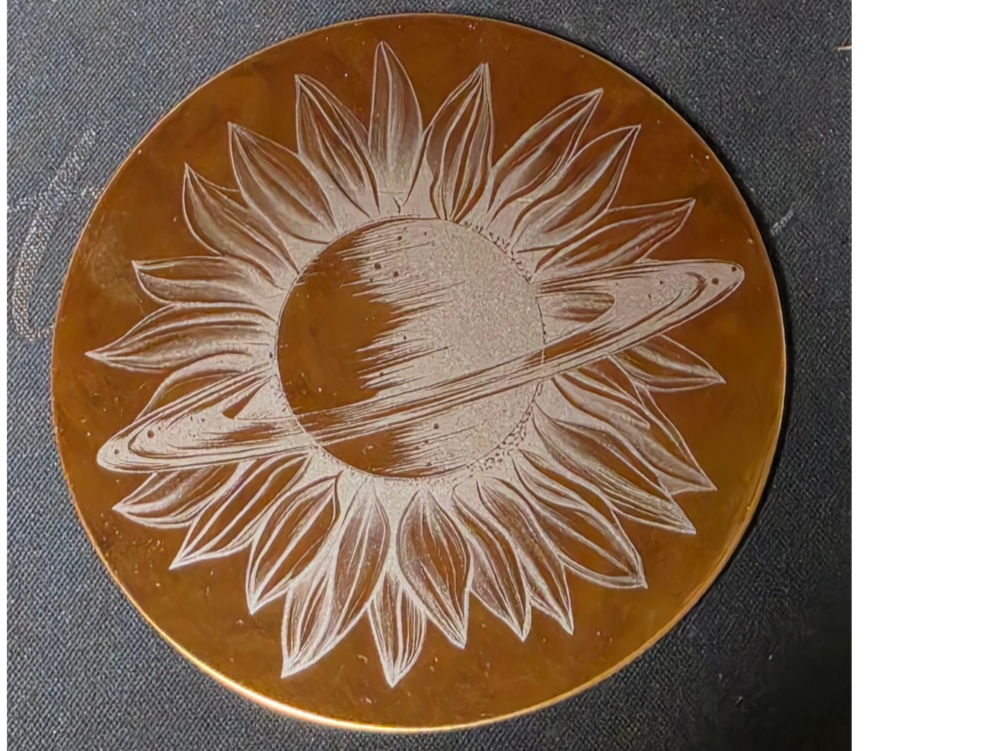 Metal coaster engraved with a sunflower set against a cosmic starfield pattern