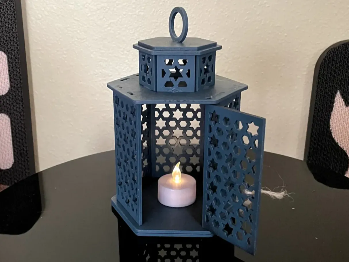 Dusty blue wooden tealight lantern with geometric star pattern cutouts and ring handle patio light idea