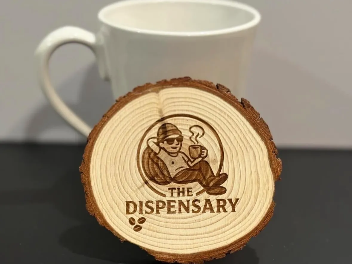 A rustic wood-slice coaster engraved with a coffee company logo