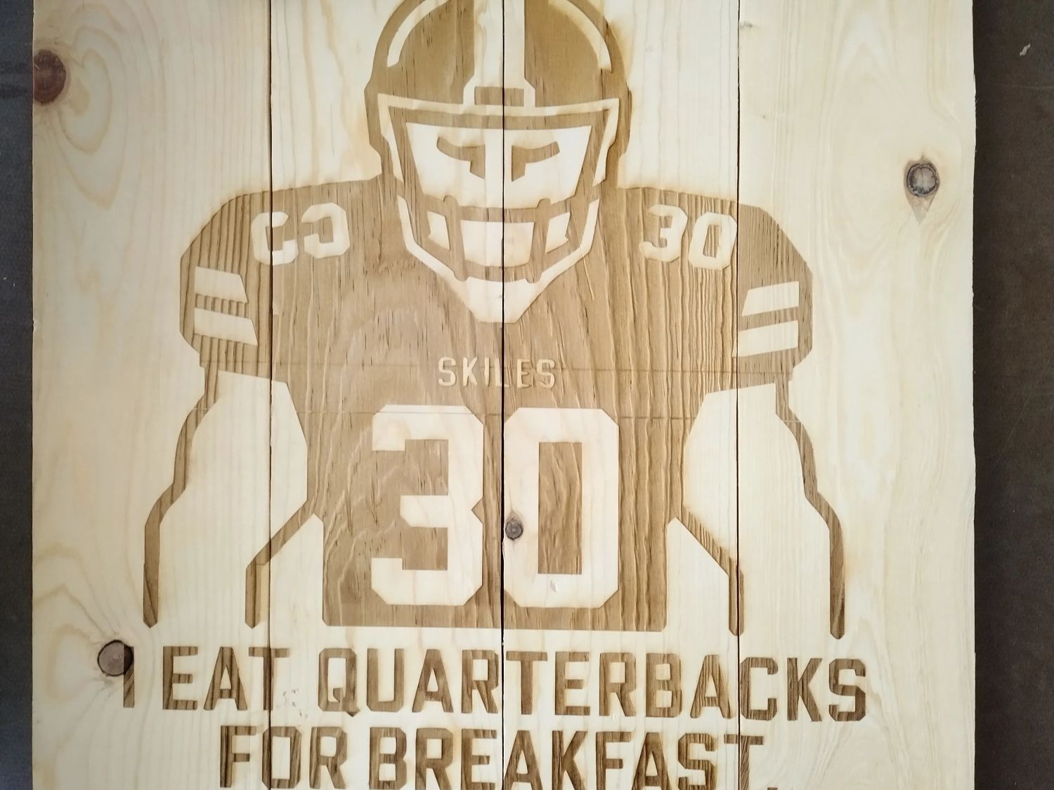 ป้ายไม้ที่มีนักฟุตบอลและข้อความ I Eat Quarterbacks For Breakfast