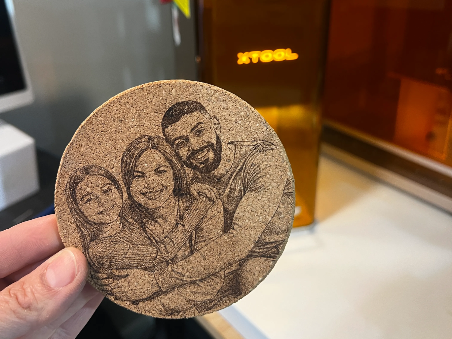 Round cork coaster engraved with a three-person family portrait
