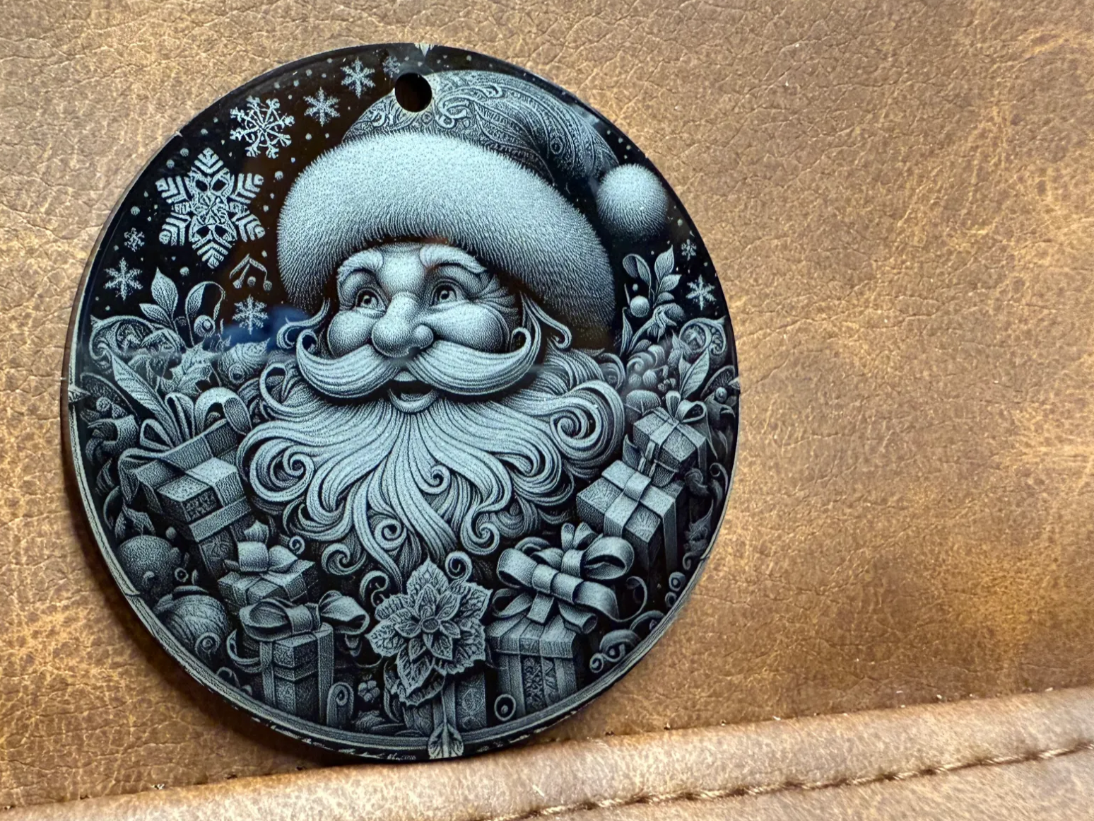 Engraved Santa Claus ornament surrounded by gifts and snowflakes