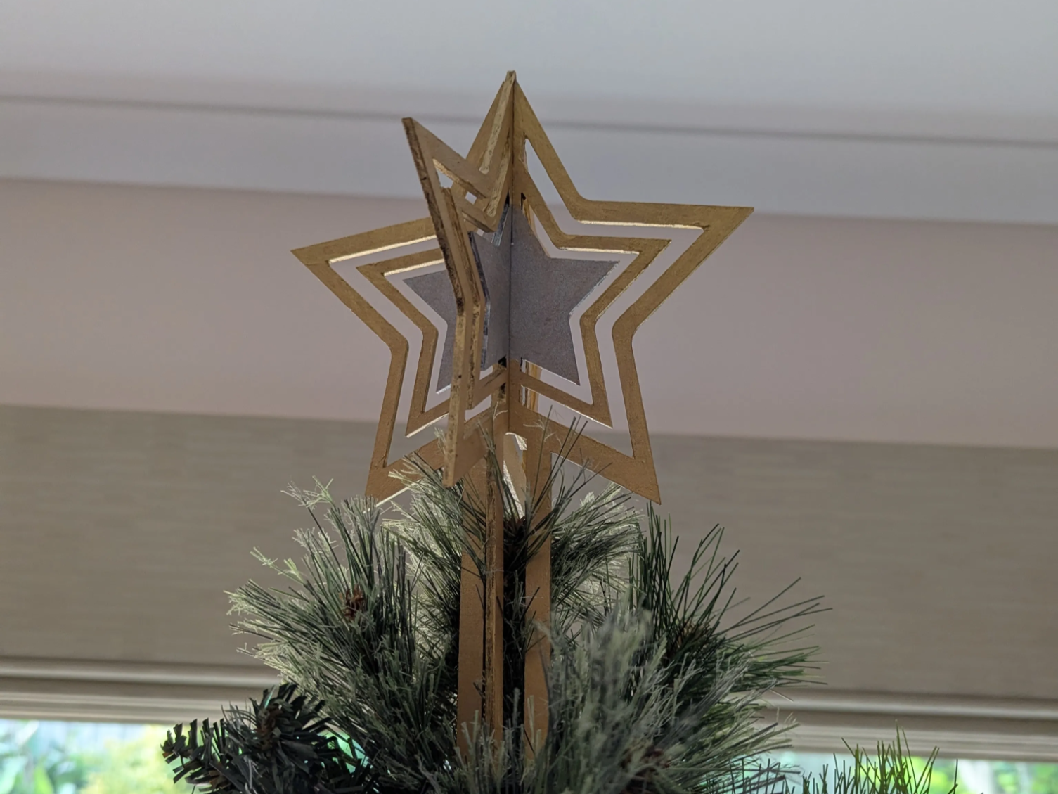 Laser-cut Christmas tree topper crowning the top of a tree