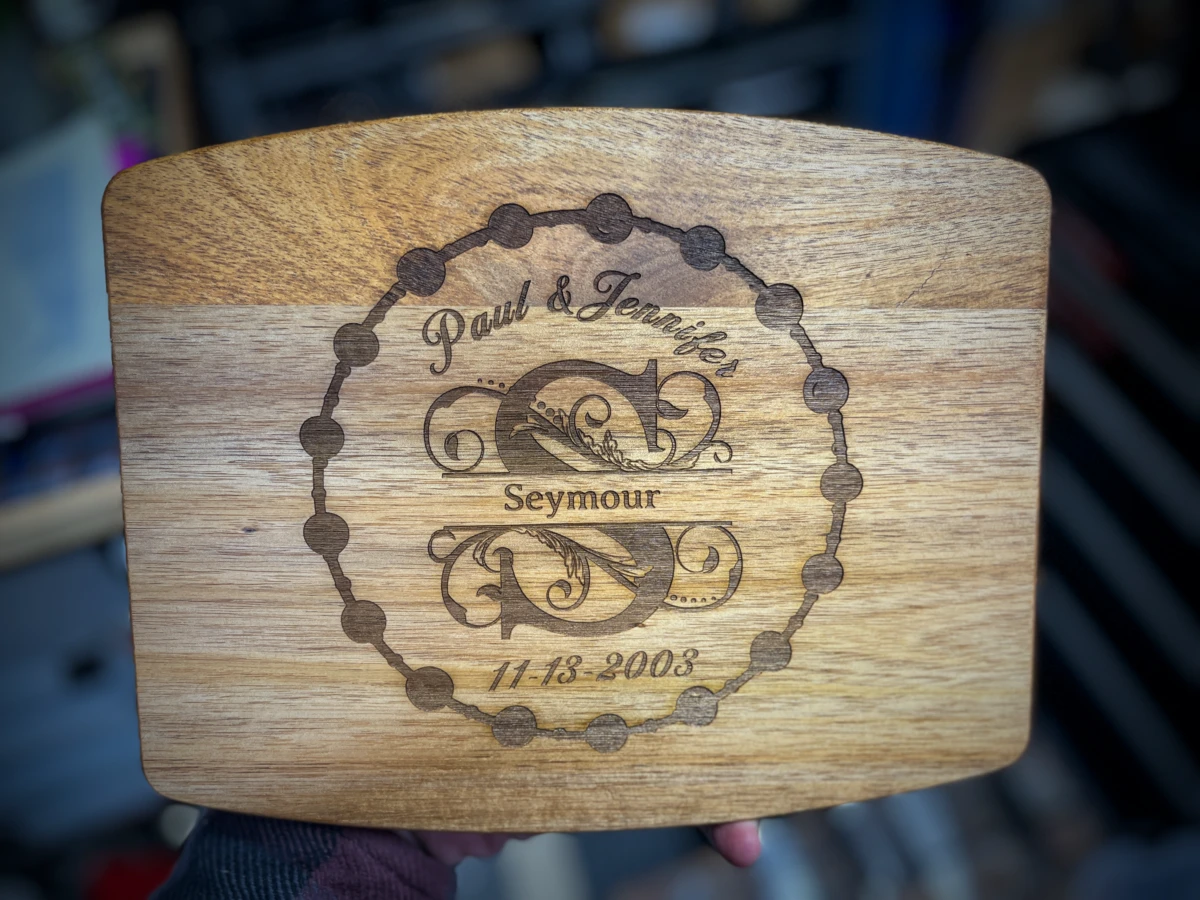 An acacia wood cutting board engraved with a monogram