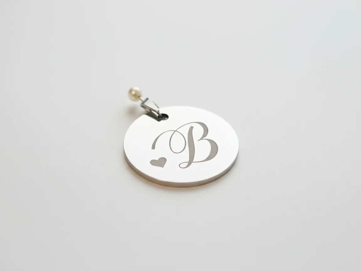 A metal pendant etched with a monogram