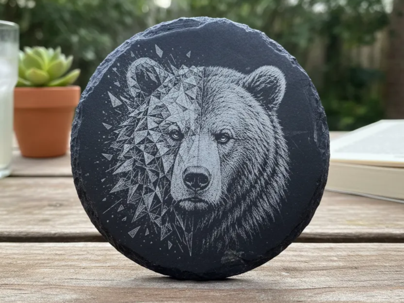 Bear portrait rendered in low-poly geometric facets on round slate coaster