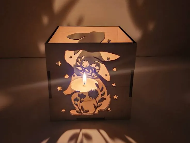 Laser cut Easter rabbit and egg tealight holder glowing on a table