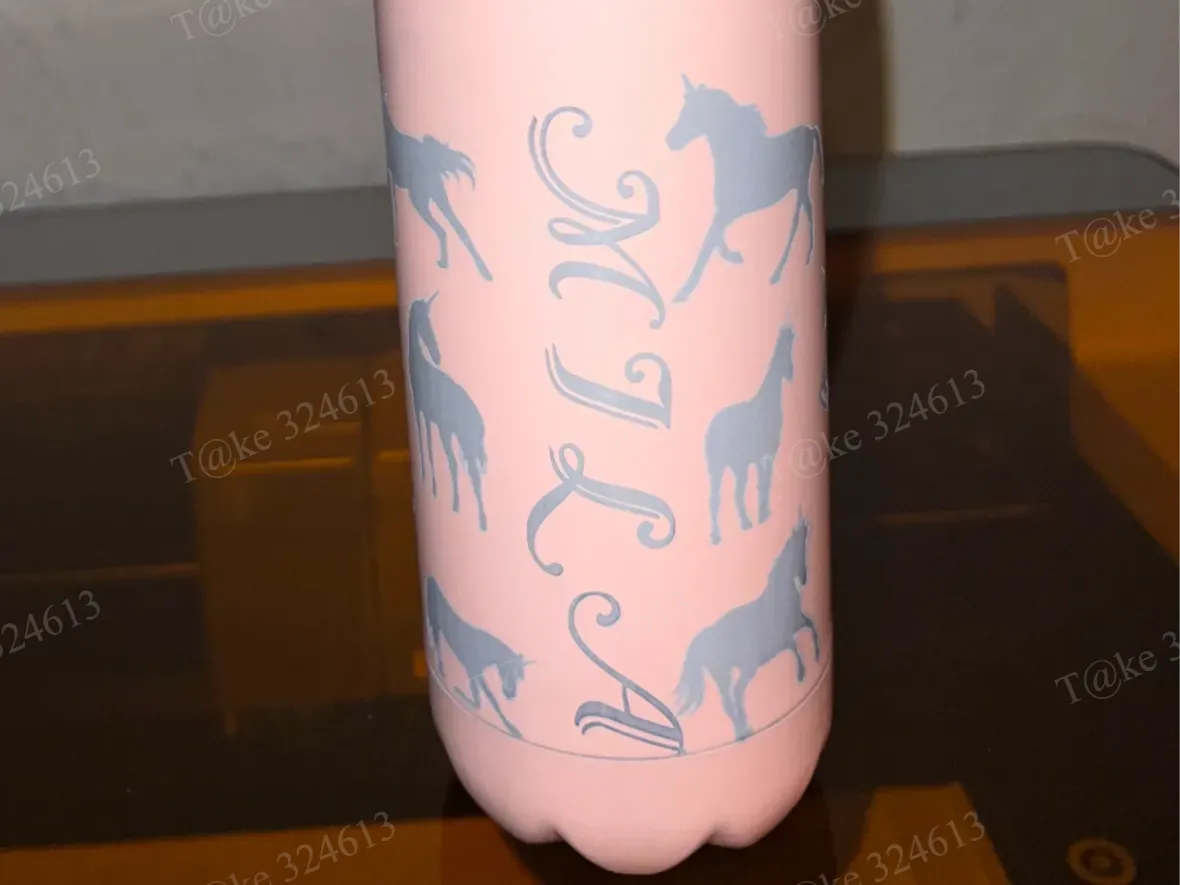 A pink soft-touch water bottle with a horse-pattern border and monogram