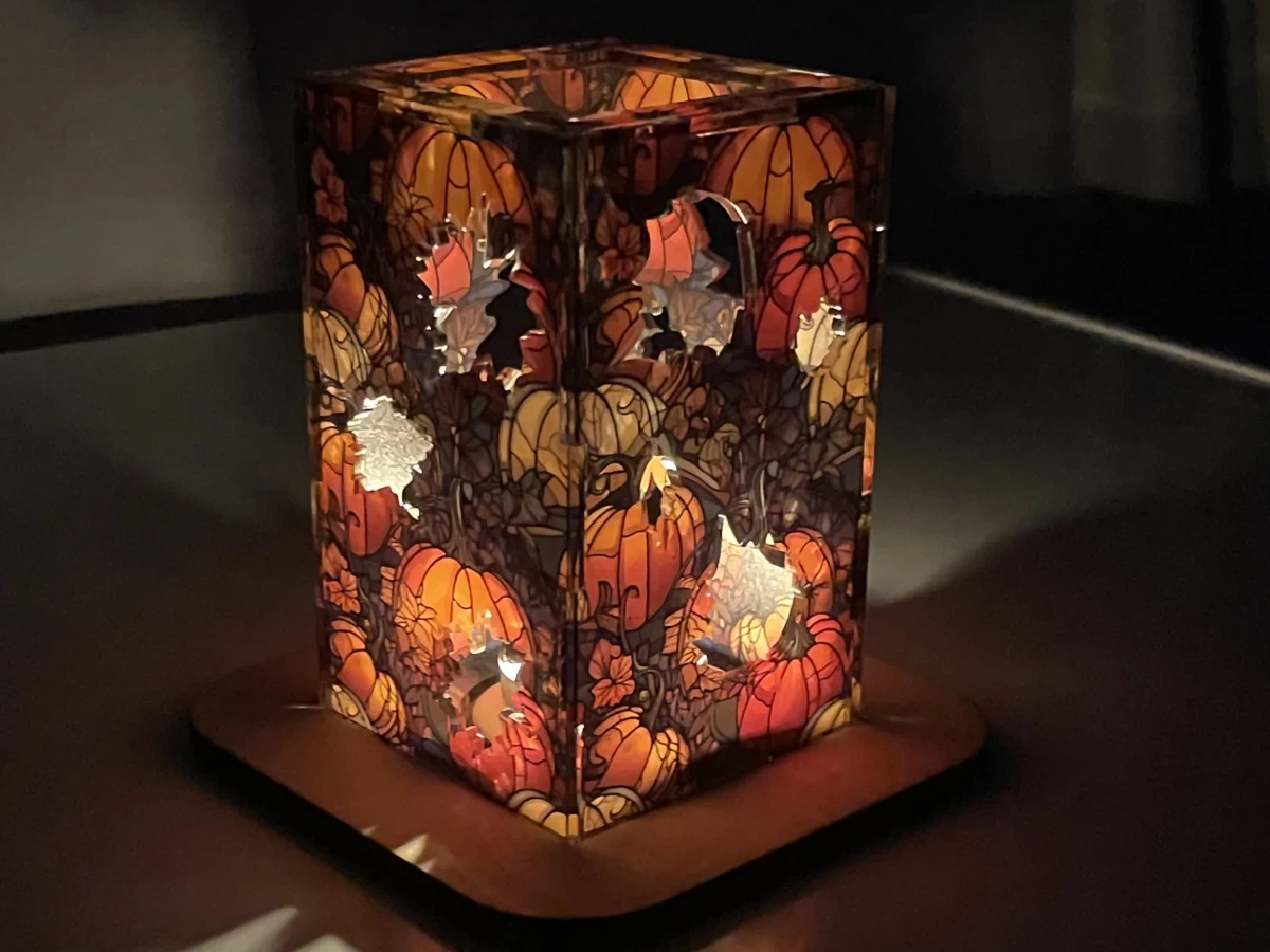 Wooden lantern with autumn pumpkins and layered leaves glowing on a base fall porch light idea