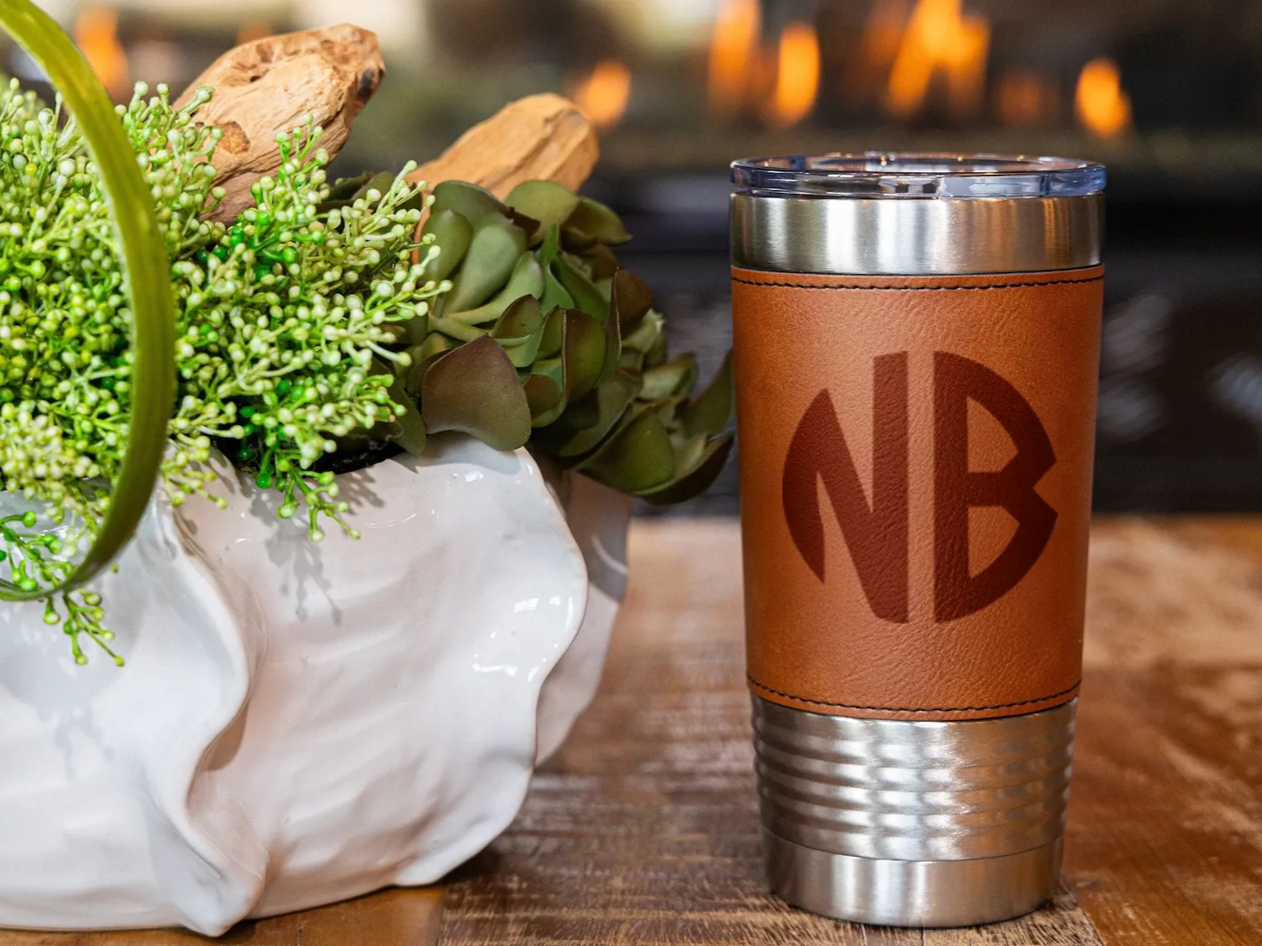 A tumbler with a leather sleeve engraved with a monogram