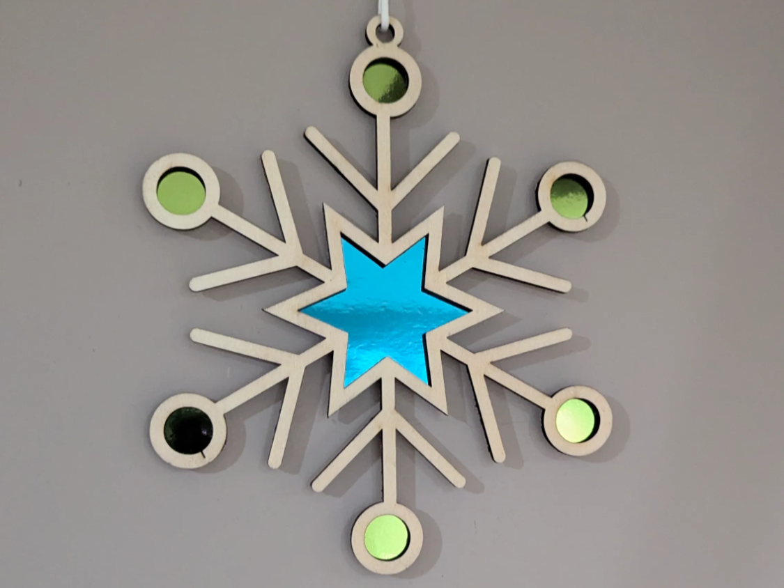 Hölzerne Schneeflocke mit Stern und Kreisen selbst gemachter Christbaumschmuck