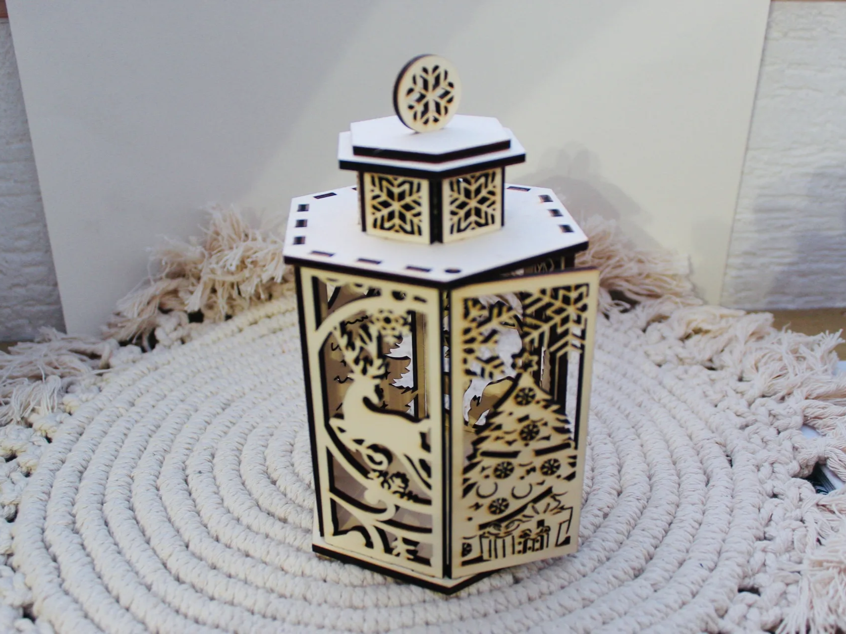 Wooden Christmas lantern with intricate cut-out designs glowing on a shelf