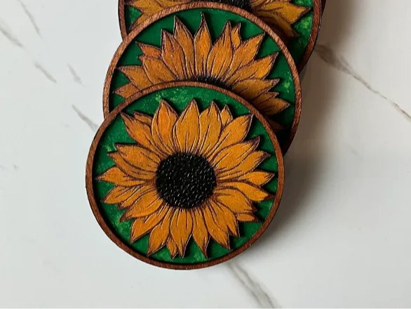 Round wooden coaster engraved with a sunflower design