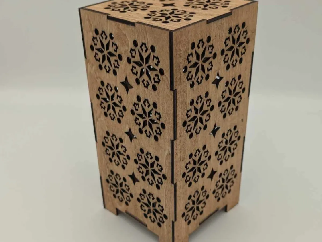 Laser cut wooden spring lantern with floral cut-outs glowing on a table