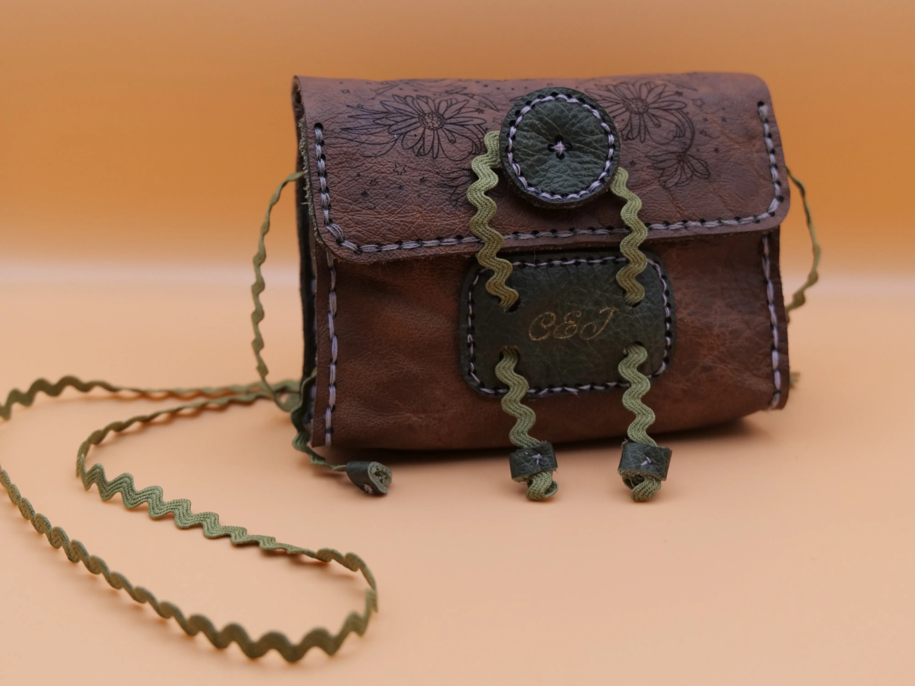 Handcrafted brown leather pouch with green strap and floral design