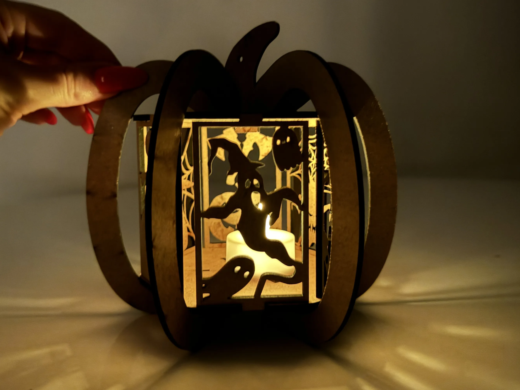 Ribbed wooden pumpkin cage lantern with witch on a broom panel glowing Halloween porch light idea