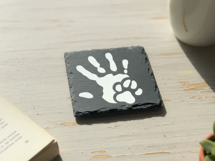 Black slate coaster with a white hand and paw print design