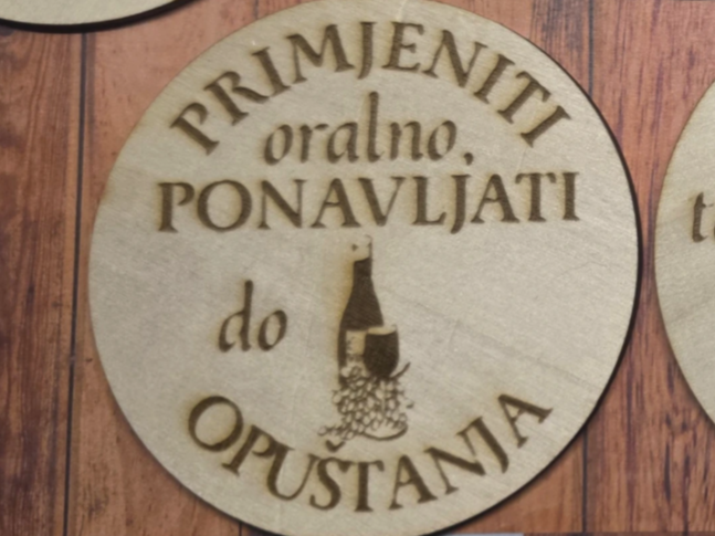 Dessous-de-verre rond en bois gravé d'une icône de bouteille et de verre à vin et d'une citation humoristique en langue slave