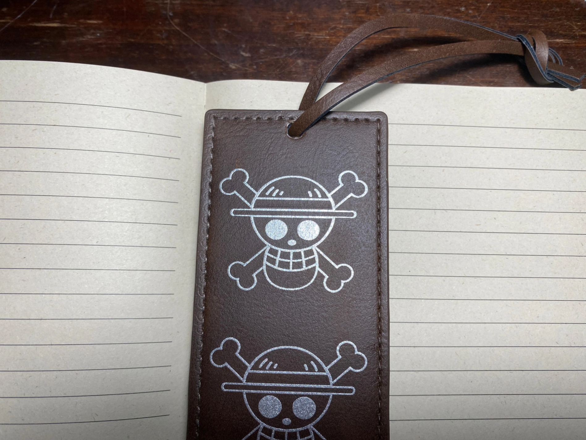 Brown leather bookmark engraved with Jolly Roger skull and crossbones repeated pattern gift idea