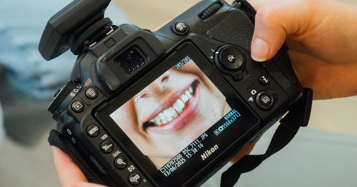A photographer reviewing a portrait on a camera screen next to a laptop