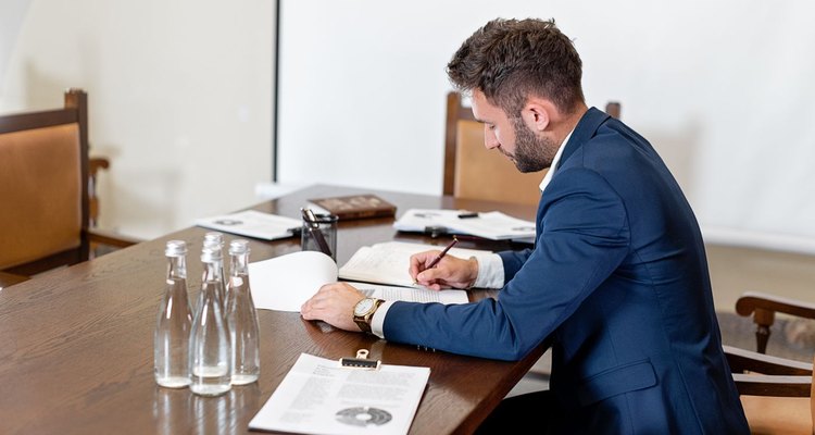 A person filling out business formation paperwork at a desk with a laptop
