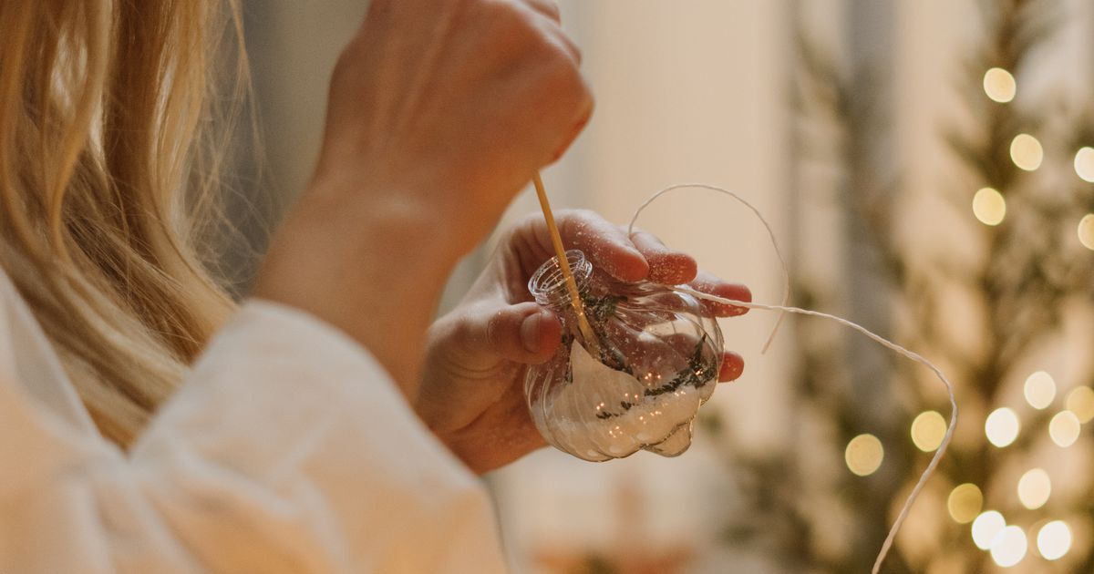A woman carefully painting a handmade Christmas ornament at a craft table