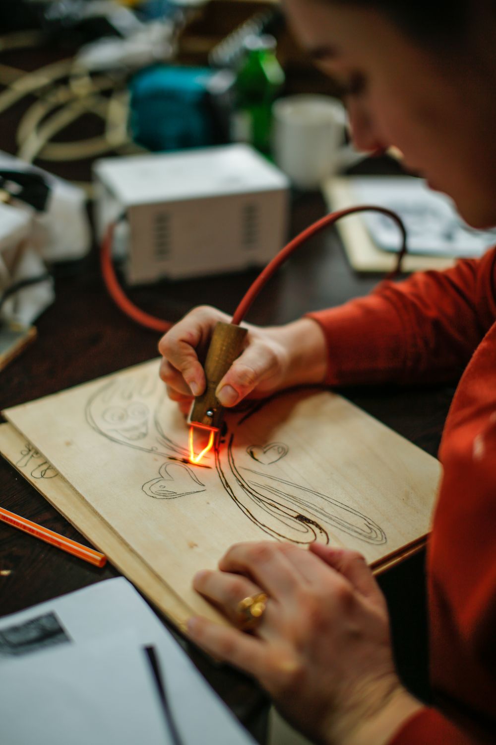 Un creatore che disegna un motivo su una tavola di legno con una penna per pirografia riscaldata