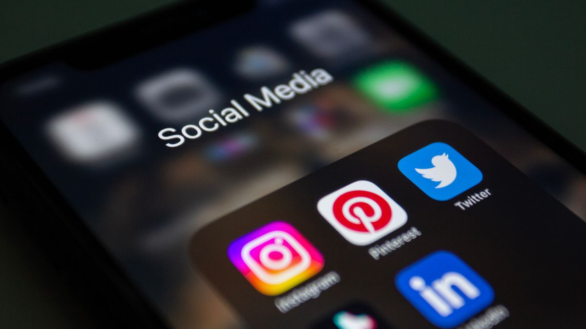 A phone showing social media apps used to market a print-on-demand business
