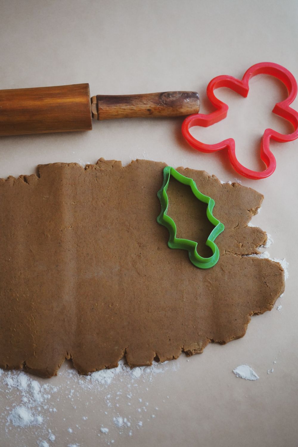 Rolled dough with star cookie cutters and a rolling pin on a floured surface