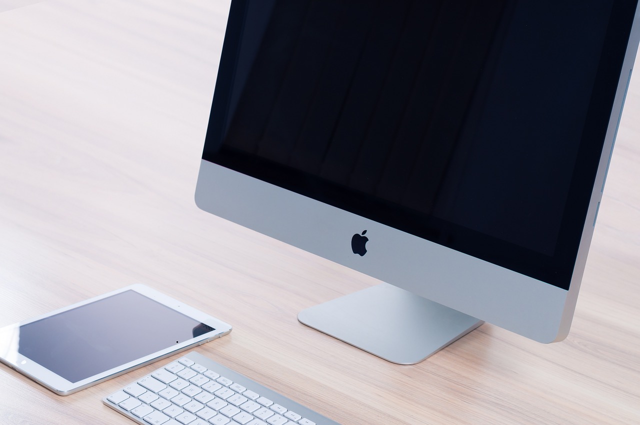 Un iMac, une tablette et un clavier sur un bureau bien rangé